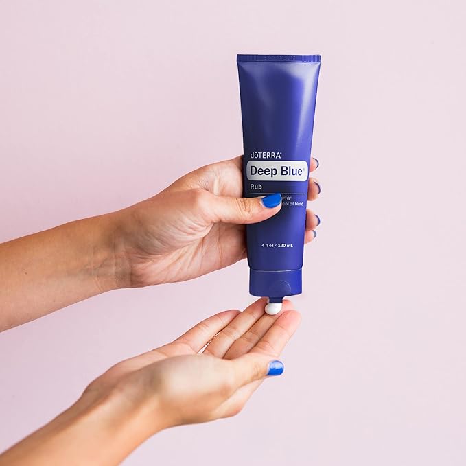 Person dispensing doTERRA Deep Blue Rub 4 oz muscle relief cream from blue tube onto hand