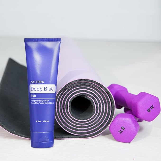 doTERRA Deep Blue Rub 4 oz tube next to a rolled pink and black yoga mat with purple 2 lb dumbbells