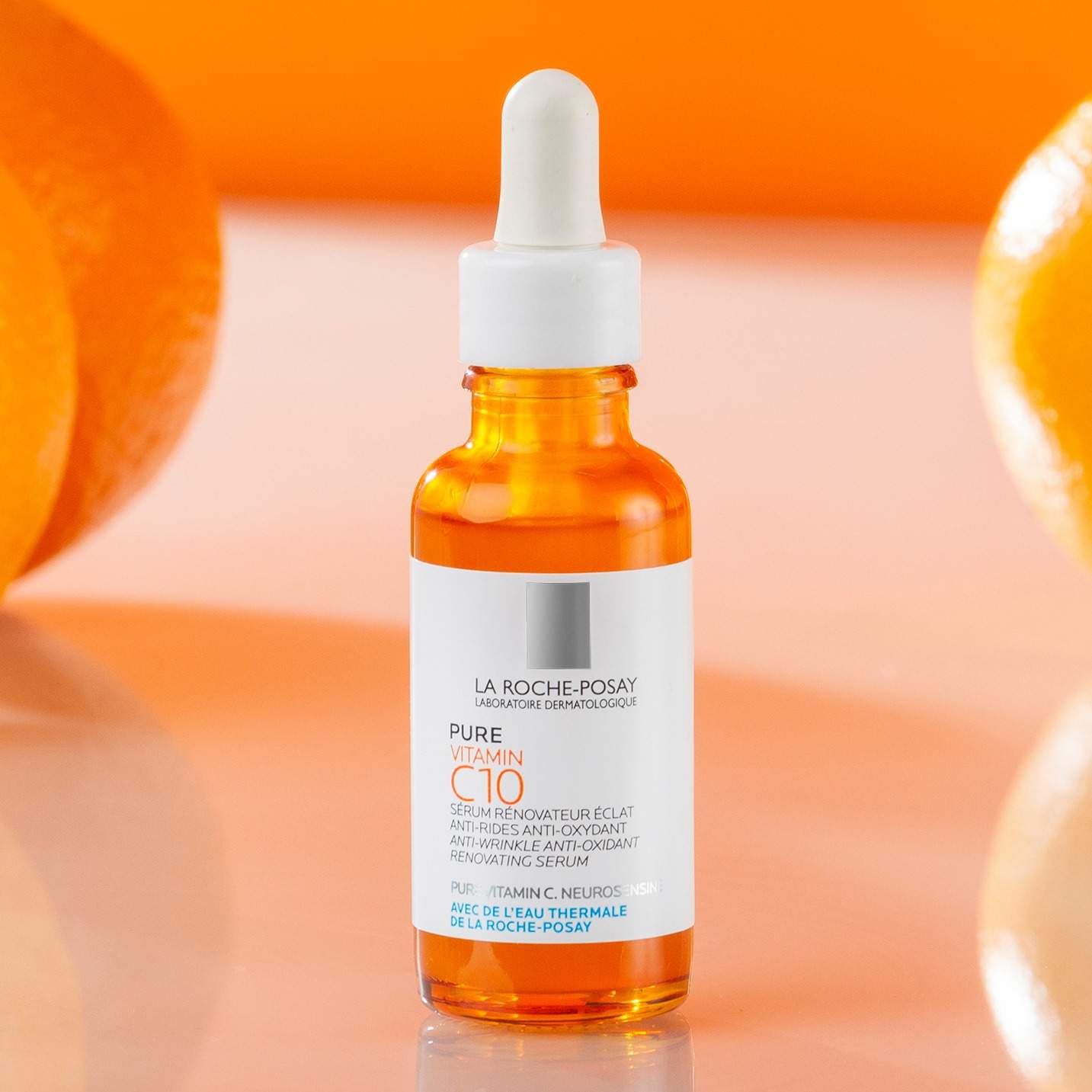 La Roche-Posay Vitamin C10 Serum in orange bottle with dropper and fresh oranges background